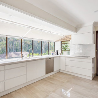 This is an example of a contemporary l-shaped kitchen in Newcastle - Maitland with an undermount sink, flat-panel cabinets, white cabinets, stainless steel appliances, no island, beige floor and white benchtop.
