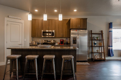 Inspiration for a large contemporary l-shaped vinyl floor and brown floor open concept kitchen remodel in Salt Lake City with an undermount sink, flat-panel cabinets, brown cabinets, granite countertops, gray backsplash, stone slab backsplash, stainless steel appliances, an island and gray countertops