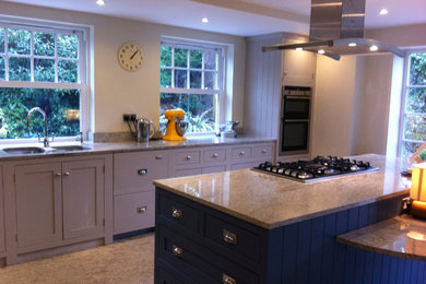 Photo of a large contemporary u-shaped kitchen/diner in Hampshire with a submerged sink, recessed-panel cabinets, blue cabinets, engineered stone countertops, stainless steel appliances, porcelain flooring and an island.