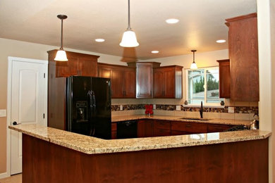 Example of a classic u-shaped kitchen design in Omaha with an undermount sink, shaker cabinets, medium tone wood cabinets, granite countertops, mosaic tile backsplash and black appliances