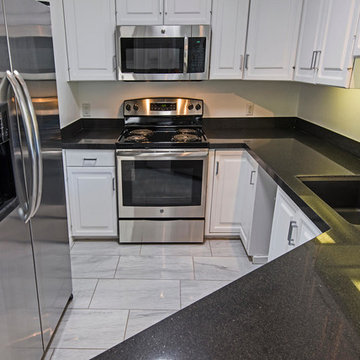 Kitchen with white painted cabinets, Carrara marble tile, black granite countert