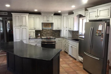 Elegant kitchen photo in Oklahoma City with white cabinets, brown backsplash, stainless steel appliances, glass tile backsplash and an island