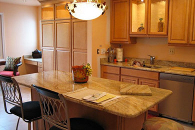 他の地域にある高級な広いおしゃれなキッチン (ダブルシンク、中間色木目調キャビネット、御影石カウンター、ベージュキッチンパネル、シルバーの調理設備、セラミックタイルの床) の写真
