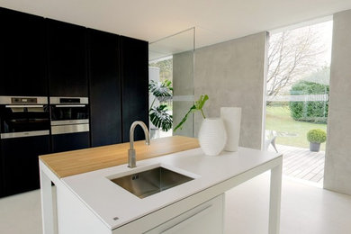 Modern inredning av ett kök och matrum, med en nedsänkt diskho, vita vitvaror, en köksö och vitt golv