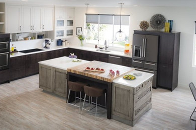 Design ideas for a large classic l-shaped kitchen/diner in Vancouver with a submerged sink, flat-panel cabinets, dark wood cabinets, black appliances, light hardwood flooring and an island.