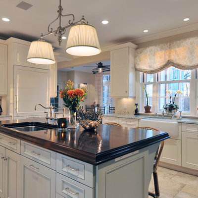 Example of a large classic l-shaped travertine floor eat-in kitchen design in New York with an undermount sink, wood countertops, recessed-panel cabinets, white cabinets, multicolored backsplash, ceramic backsplash, stainless steel appliances and an island