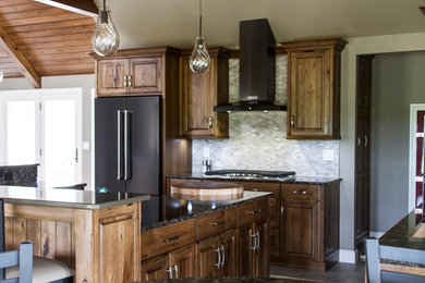 Example of a large mountain style l-shaped porcelain tile and gray floor eat-in kitchen design in Columbus with an undermount sink, raised-panel cabinets, medium tone wood cabinets, granite countertops, multicolored backsplash, stainless steel appliances, an island and stone tile backsplash