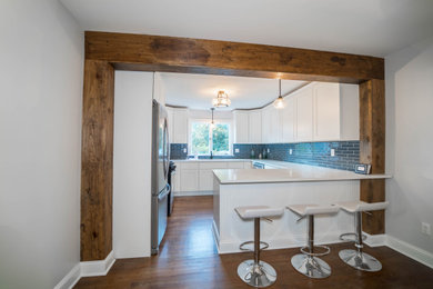 Trendy medium tone wood floor and brown floor eat-in kitchen photo in New York with an undermount sink, shaker cabinets, white cabinets, quartz countertops, blue backsplash, glass tile backsplash, stainless steel appliances, a peninsula and white countertops