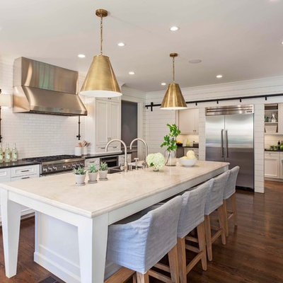 Transitional dark wood floor kitchen photo in Charlotte with a double-bowl sink, recessed-panel cabinets, white cabinets, solid surface countertops, white backsplash, subway tile backsplash, stainless steel appliances and an island