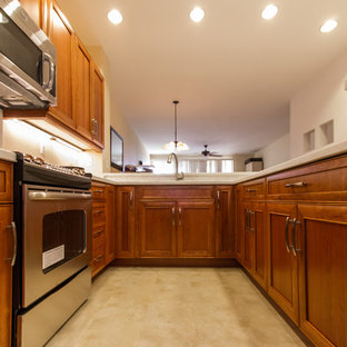 Photo of a mid-sized asian u-shaped eat-in kitchen in Hawaii with an undermount sink, recessed-panel cabinets, medium wood cabinets, limestone benchtops, white splashback, stone slab splashback, stainless steel appliances, no island, laminate floors and beige floor.