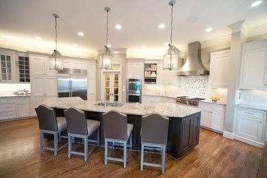 Large transitional l-shaped medium tone wood floor enclosed kitchen photo in Birmingham with white cabinets, granite countertops, white backsplash, subway tile backsplash, stainless steel appliances, an island, a double-bowl sink and beaded inset cabinets