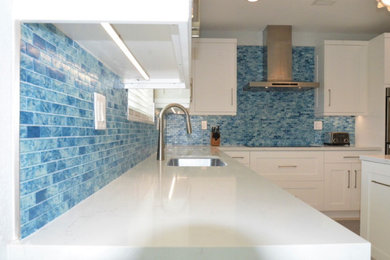 Example of a mid-sized minimalist u-shaped porcelain tile and white floor eat-in kitchen design in Miami with an undermount sink, shaker cabinets, white cabinets, quartzite countertops, blue backsplash, mosaic tile backsplash, stainless steel appliances, an island and white countertops