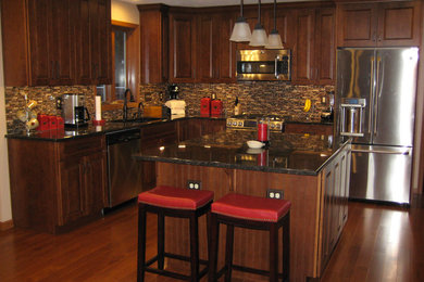 Klassisk inredning av ett mellanstort kök, med en köksö, en undermonterad diskho, luckor med upphöjd panel, skåp i mörkt trä, granitbänkskiva, flerfärgad stänkskydd, stänkskydd i glaskakel, rostfria vitvaror och mellanmörkt trägolv