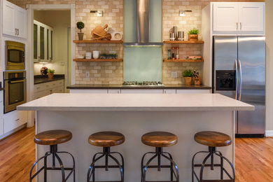ヒューストンにある広いコンテンポラリースタイルのおしゃれなキッチン (シェーカースタイル扉のキャビネット、白いキャビネット、ベージュキッチンパネル、サブウェイタイルのキッチンパネル、シルバーの調理設備、無垢フローリング) の写真