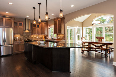 Example of a classic eat-in kitchen design in Cleveland with flat-panel cabinets, medium tone wood cabinets, granite countertops, beige backsplash and stainless steel appliances