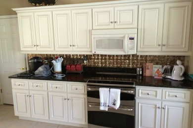 オーランドにある中くらいなおしゃれなI型キッチン (レイズドパネル扉のキャビネット、白いキャビネット、茶色いキッチンパネル、シルバーの調理設備) の写真