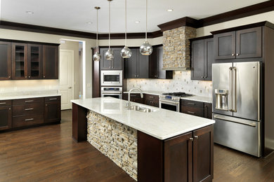 Example of a mid-sized trendy l-shaped medium tone wood floor and brown floor open concept kitchen design in Other with an undermount sink, recessed-panel cabinets, white cabinets, quartzite countertops, white backsplash, ceramic backsplash, stainless steel appliances and an island