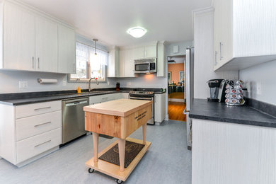 This is an example of a medium sized classic u-shaped kitchen/diner in Ottawa with a built-in sink, flat-panel cabinets, grey cabinets, laminate countertops, stainless steel appliances, lino flooring and an island.
