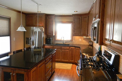 Kitchen - medium tone wood floor kitchen idea in Kansas City with medium tone wood cabinets, beige backsplash, stainless steel appliances and an island