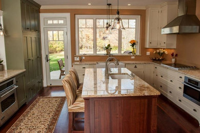 Inspiration for a mid-sized transitional u-shaped medium tone wood floor enclosed kitchen remodel in Boston with a farmhouse sink, shaker cabinets, white cabinets, granite countertops, stainless steel appliances and an island