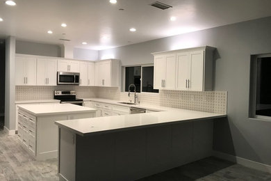 Inspiration for a mid-sized transitional u-shaped light wood floor and gray floor eat-in kitchen remodel in San Diego with an undermount sink, shaker cabinets, white cabinets, solid surface countertops, white backsplash, porcelain backsplash, stainless steel appliances, an island and white countertops