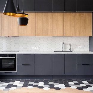 Inspiration for a mid-sized contemporary l-shaped separate kitchen in Toronto with an undermount sink, flat-panel cabinets, white splashback, light wood cabinets, quartz benchtops, porcelain splashback, black appliances, porcelain floors, with island, multi-coloured floor and grey benchtop.