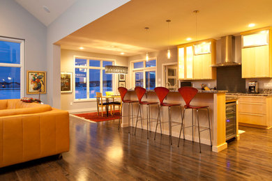 Cette image montre une cuisine linéaire design en bois clair avec un électroménager en acier inoxydable, un sol en bois brun et îlot.
