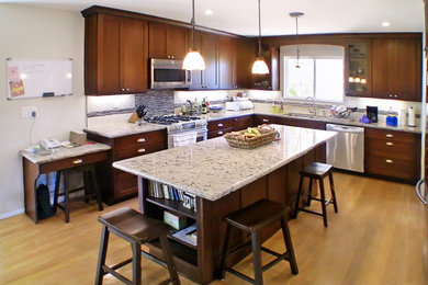 Example of a mid-sized transitional l-shaped light wood floor kitchen design in Santa Barbara with a double-bowl sink, shaker cabinets, medium tone wood cabinets, granite countertops, white backsplash, stone tile backsplash, stainless steel appliances and an island