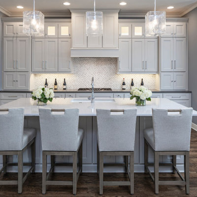 Large transitional l-shaped brown floor and dark wood floor open concept kitchen photo in Kansas City with an undermount sink, shaker cabinets, white cabinets, quartzite countertops, mosaic tile backsplash, stainless steel appliances, an island, white backsplash and gray countertops