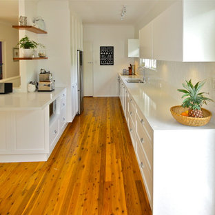 Inspiration for a mid-sized modern galley eat-in kitchen in Sydney with an undermount sink, shaker cabinets, white cabinets, quartz benchtops, white splashback, terra-cotta splashback, stainless steel appliances and medium hardwood floors.