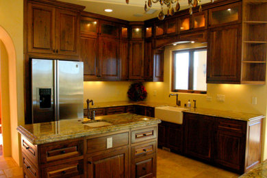 Large elegant u-shaped beige floor enclosed kitchen photo in Albuquerque with a farmhouse sink, raised-panel cabinets, dark wood cabinets, granite countertops, stainless steel appliances and an island