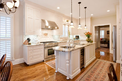 Inspiration for a large transitional l-shaped medium tone wood floor eat-in kitchen remodel in Charleston with a farmhouse sink, stainless steel appliances, cement tile backsplash, white backsplash, raised-panel cabinets, white cabinets, granite countertops and an island