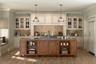Example of a classic light wood floor kitchen design in Chicago with glass-front cabinets, white cabinets, beige backsplash, paneled appliances and an island