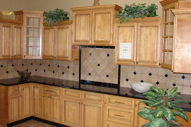 Modelo de cocina lineal con armarios con paneles empotrados, puertas de armario de madera clara, encimera de granito, salpicadero beige, salpicadero de azulejos de cerámica y electrodomésticos negros