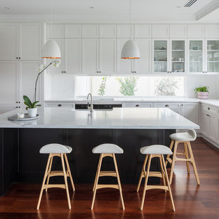 This is an example of a transitional l-shaped kitchen in Perth with a farmhouse sink, shaker cabinets, white cabinets, window splashback, medium hardwood floors, with island and brown floor.