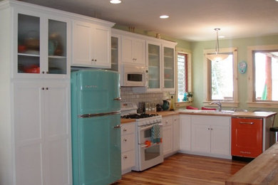 Große Küche mit Vorratsschrank, Doppelwaschbecken, Schrankfronten mit vertiefter Füllung, weißen Schränken, Arbeitsplatte aus Holz, hellem Holzboden und Kücheninsel in Denver