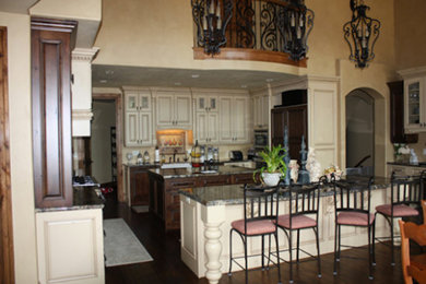 Example of an u-shaped kitchen design in Salt Lake City with white cabinets, granite countertops, beige backsplash and an island