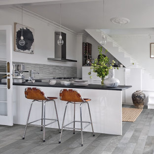 Small eclectic kitchen in Denver with flat-panel cabinets, white cabinets, porcelain splashback, stainless steel appliances, porcelain floors, a peninsula and grey floor.