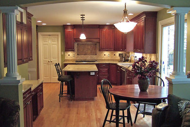 Inspiration for a mid-sized transitional l-shaped light wood floor eat-in kitchen remodel in Chicago with an undermount sink, raised-panel cabinets, medium tone wood cabinets, beige backsplash, ceramic backsplash, stainless steel appliances and an island