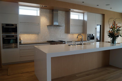 Inspiration for a mid-sized contemporary u-shaped light wood floor and beige floor eat-in kitchen remodel in Denver with an undermount sink, flat-panel cabinets, white cabinets, quartz countertops, white backsplash, mosaic tile backsplash, stainless steel appliances, an island and white countertops