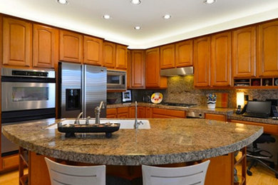 Inspiration for a large l-shaped medium tone wood floor eat-in kitchen remodel in Other with an undermount sink, raised-panel cabinets, medium tone wood cabinets, granite countertops, beige backsplash, stone slab backsplash, stainless steel appliances and an island