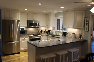 Eat-in kitchen - mid-sized traditional light wood floor eat-in kitchen idea in Providence with an undermount sink, raised-panel cabinets, white cabinets, granite countertops, white backsplash, subway tile backsplash, stainless steel appliances and a peninsula