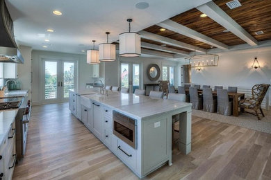 Open concept kitchen - large galley light wood floor and beige floor open concept kitchen idea in Miami with a farmhouse sink, recessed-panel cabinets, white cabinets, marble countertops, stainless steel appliances and an island