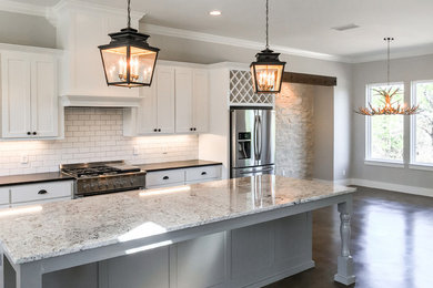 Example of a large country concrete floor open concept kitchen design in Austin with shaker cabinets, granite countertops, white backsplash, subway tile backsplash, stainless steel appliances, an island and white cabinets