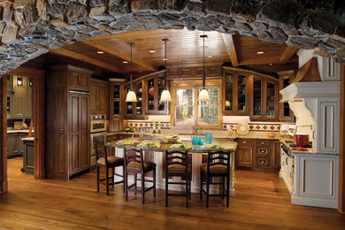 Diseño de cocina clásica con puertas de armario de madera en tonos medios, encimera de granito, salpicadero beige, suelo de madera en tonos medios y una isla
