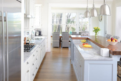Inspiration for a coastal kitchen in Charleston with a built-in sink, shaker cabinets, white cabinets, wood worktops, white splashback, stainless steel appliances, medium hardwood flooring and an island.