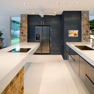 Photo of an expansive modern galley eat-in kitchen in Milwaukee with flat-panel cabinets, black cabinets, with island, an undermount sink, limestone benchtops, black splashback, stone tile splashback, stainless steel appliances and ceramic floors.