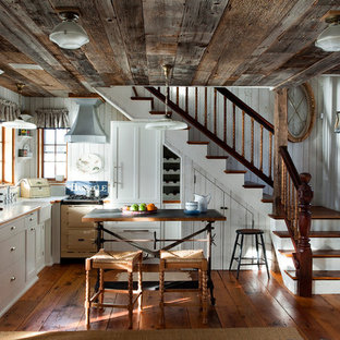 Esempio di una cucina a L country con lavello stile country, ante lisce, ante bianche, pavimento in legno massello medio e isola
