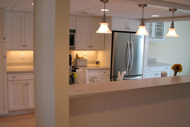 Foto di una cucina chic di medie dimensioni con ante con riquadro incassato, ante bianche, top in superficie solida, elettrodomestici in acciaio inossidabile e pavimento in legno massello medio