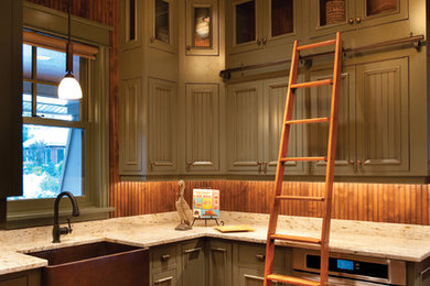 Rustik inredning av ett mellanstort, avskilt u-kök, med en rustik diskho, gröna skåp, granitbänkskiva, brunt stänkskydd, rostfria vitvaror, mellanmörkt trägolv, stänkskydd i trä och luckor med profilerade fronter